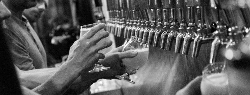 Bartenders pouring beer from rows of beer taps