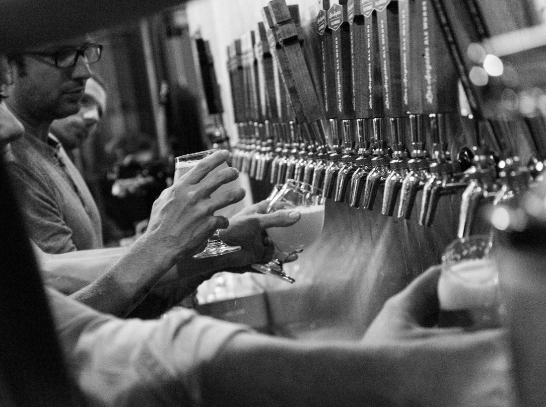 Bartenders pouring beer from rows of beer taps