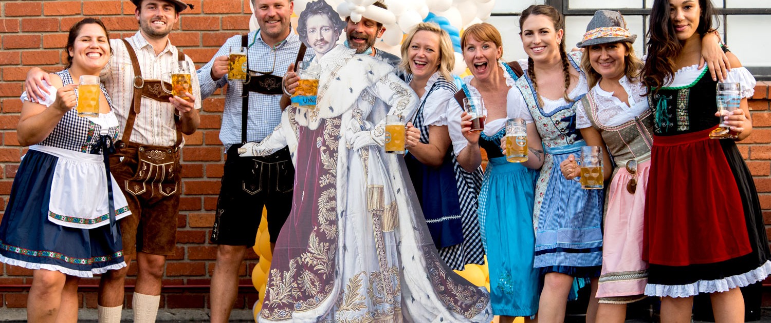 Group of people dressed in Oktoberfest outfits w/ beer steins