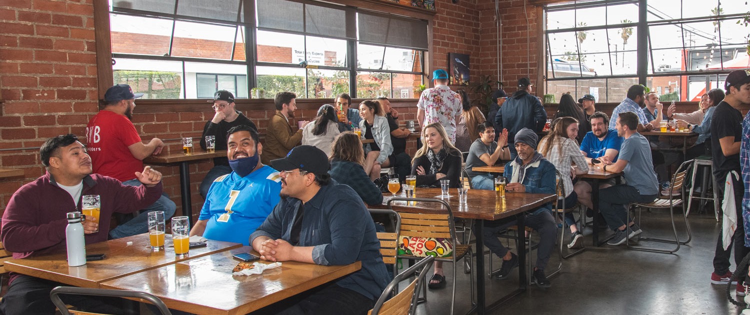 People sitting at tables inside the LA Ale Works taproom