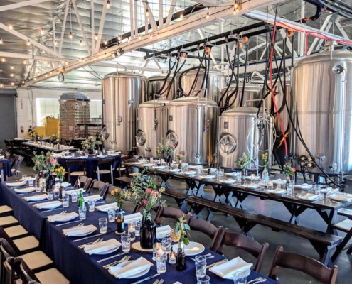 Tables set up for a special event with a production brewery in background