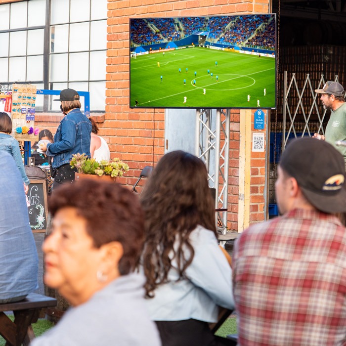 People watching a soccer match on a big tv screen