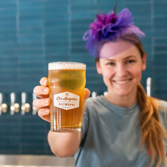 Woman wearing a fancy fascinator holding a beer